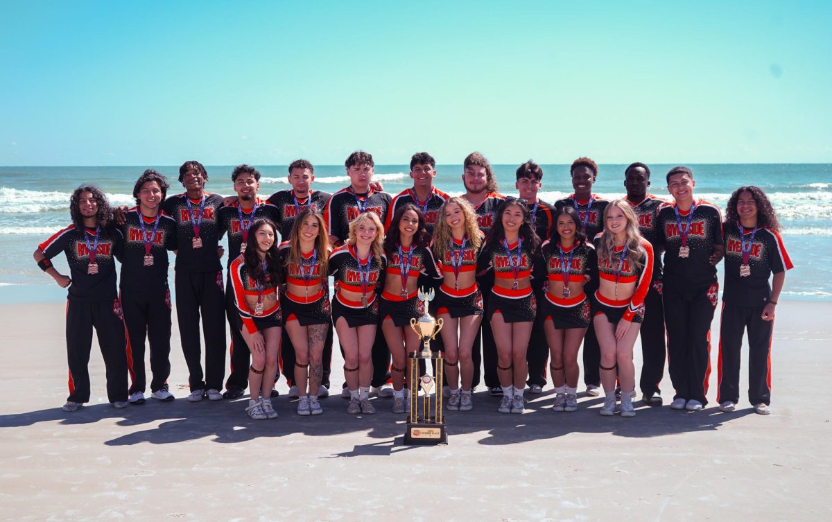 The Riverside City College co-ed team posing in front of their trophy after taking 2nd place at Daytona National Cheerleaders Association College Nationals.