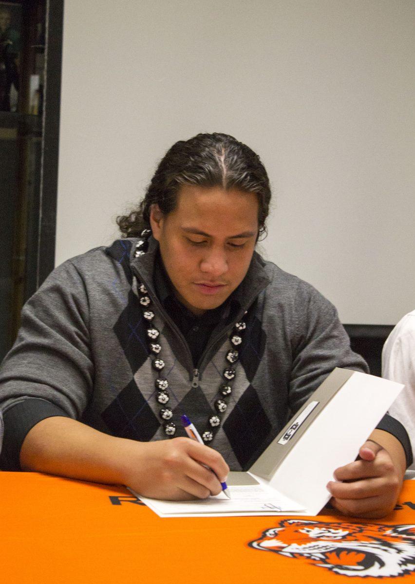 Signed: Tigers' Edmund Faimalo signs his letter of intent to play football at Utah State on Feb. 6 in RCC's Hall of Fame Room(Photo by Luis Solis)