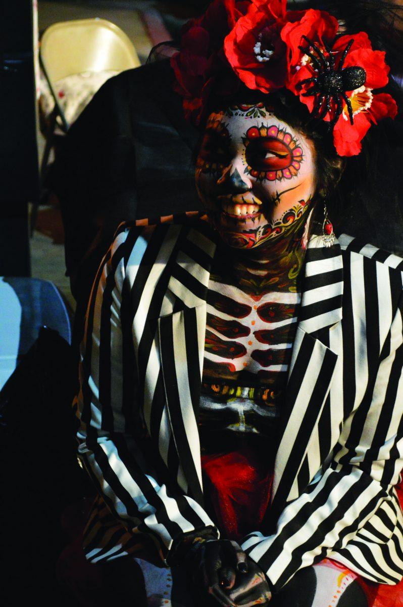 Rebekah Josoh warms up in the cool evening of  Dia de los Muertos in a striped jacket reminiscent of the undead character in Tim Burton’s “Beetlejuice”