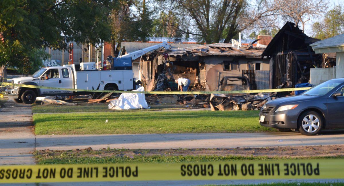 The morning after a plane crashed on Rhonda Road, Riverside city workers sift through the ashy rubble of the four affected homes Feb. 28. (Chris Edson | Viewpoints)