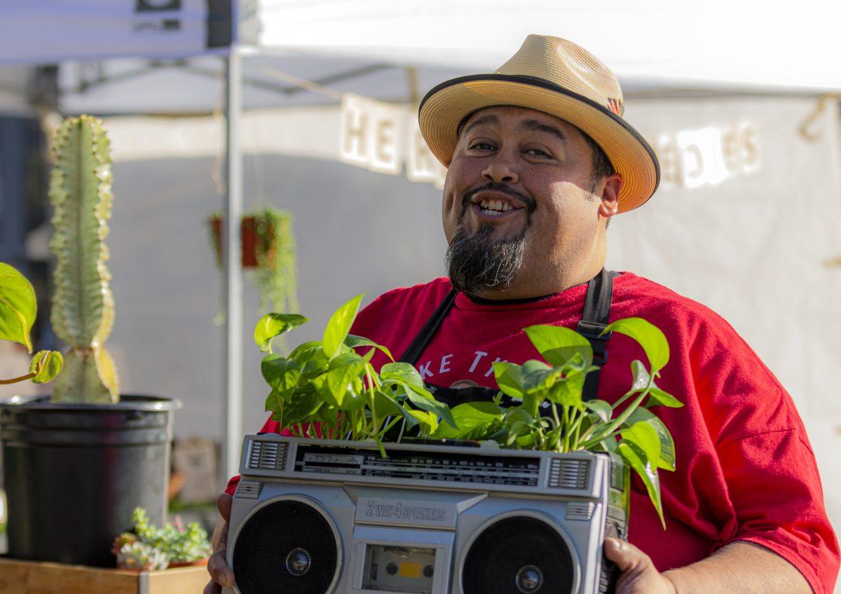 Jesse Monstera, stands in front of his Succs 2 B You plant pop stand with his boombox planter, which blends his hip hop and Chicano culture with his love of plants, at pop-up event held at the Jurupa Valley Spectrum on March 18. (Stephen Day | Viewpoints)