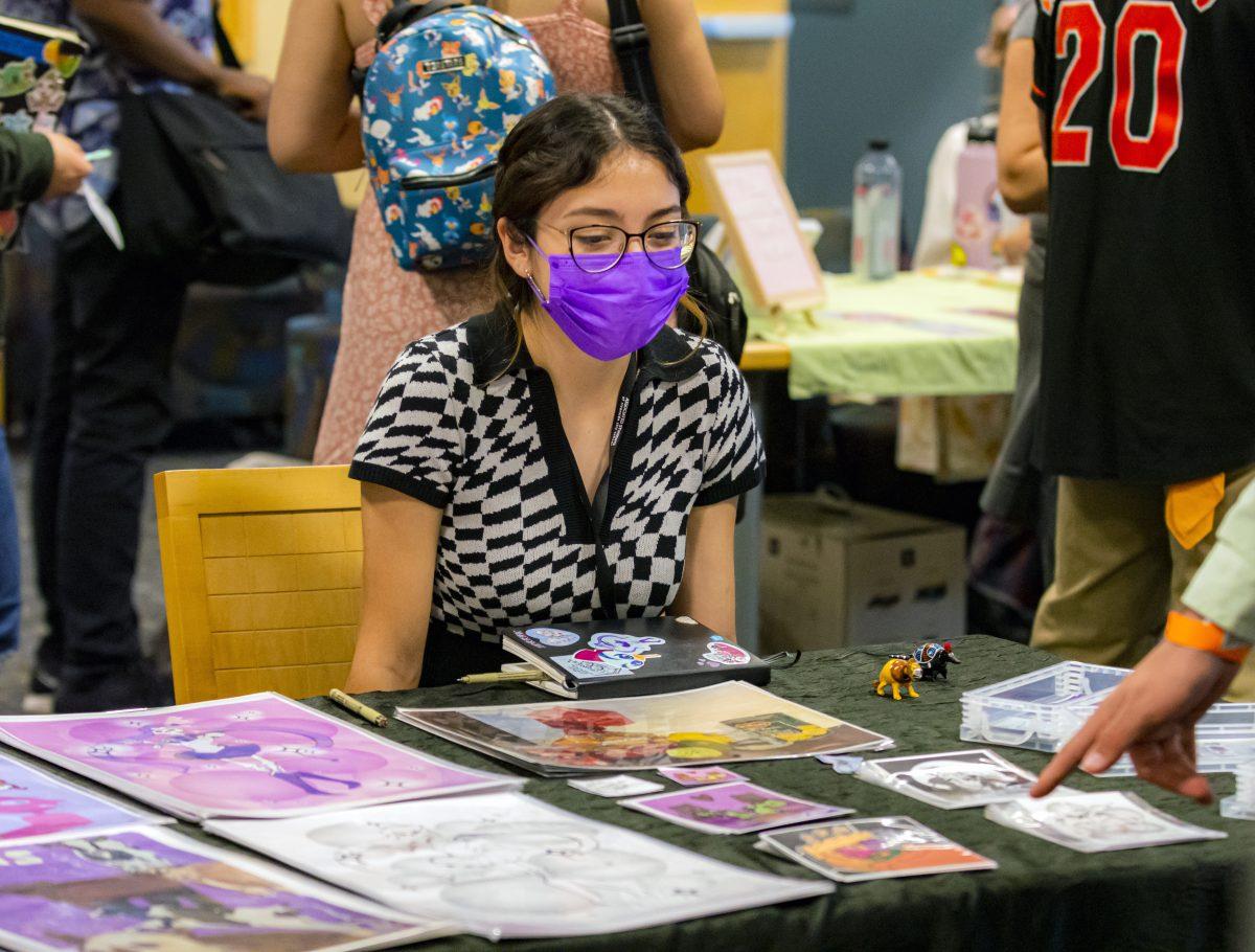 Daniela Arbarca, artist, sits a her table displaying her artwork, available for sale at TigerCon, a Comic-Con style event held at the Salvatore G. Rotella Digital Library and Learning Resource Center at Riverside City College on April 5. Photo by Stephen Day, Viewpoints.