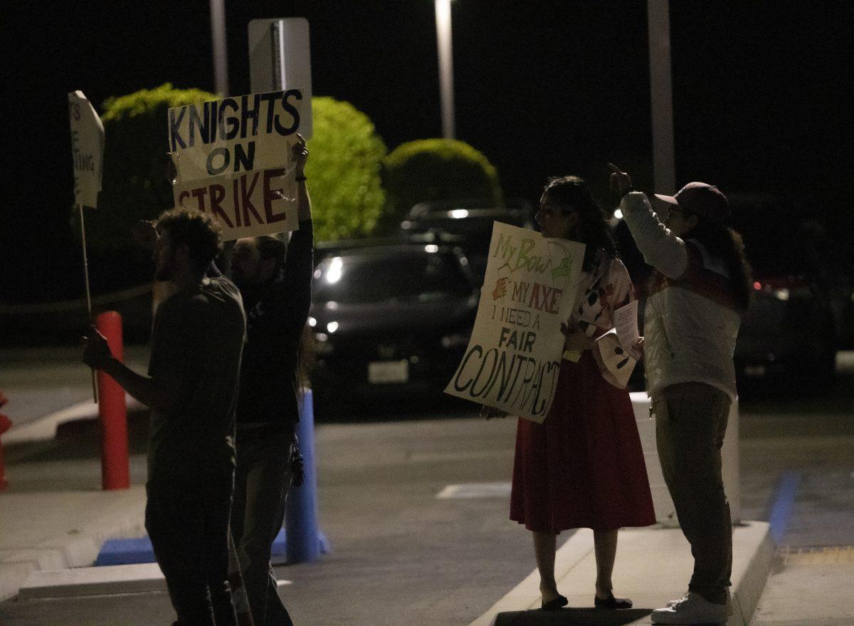 Four Medieval Times protestors stand outside in the parking lot with signs symbolizing the strike in Buena Park on March 17.
(Hayden Kulick | Viewpoints)