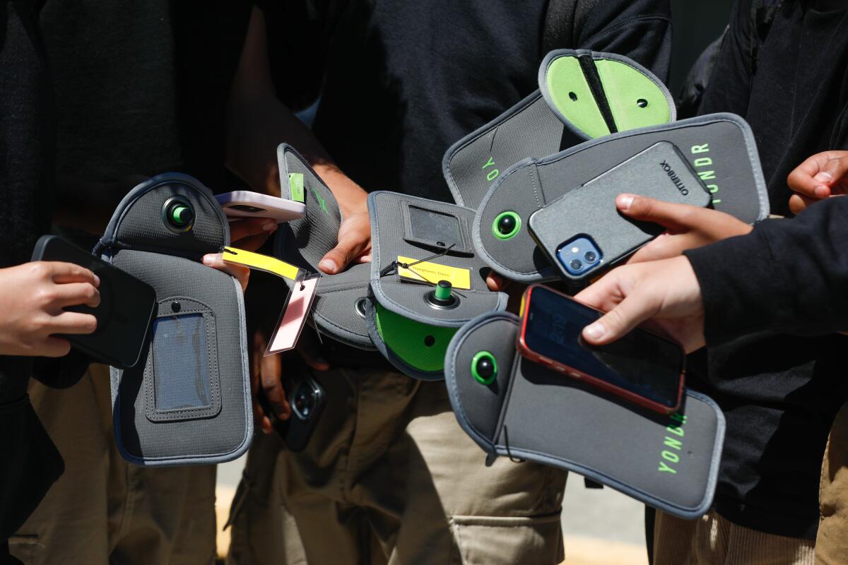 Students release their cell phones from their Yondr pouches during their free time at school. (Photo courtesy of Lea Suzuki / Getty Images)