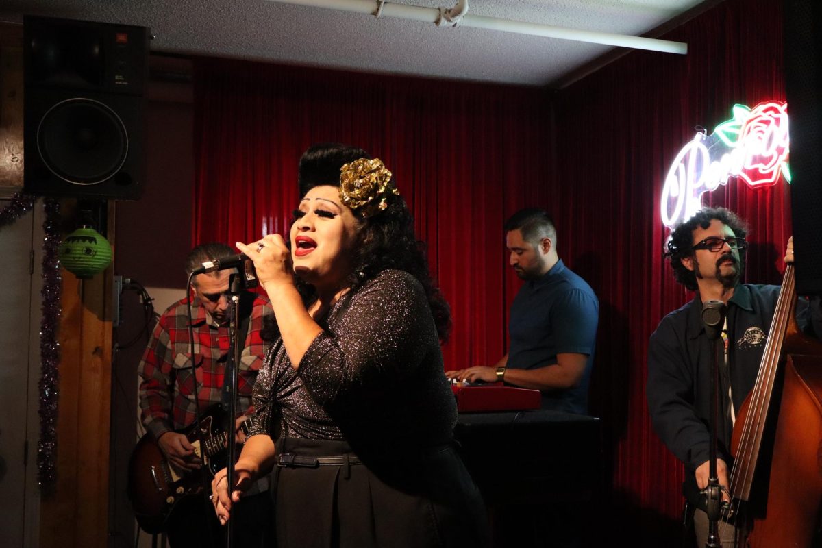 Woman singing into microphone while band plays behind her.