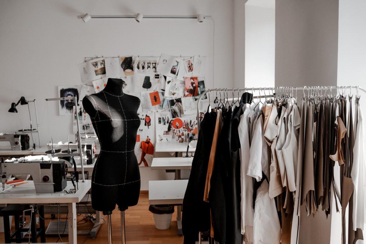 A look into a fashion designer's room filled with a sewing machine, sketches and mock-ups.