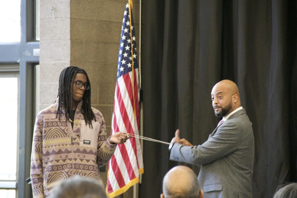 Riverside City College student assists speaker, Edward Bush, with a rubber band representing anticipatory fear during MLK Brunch. 