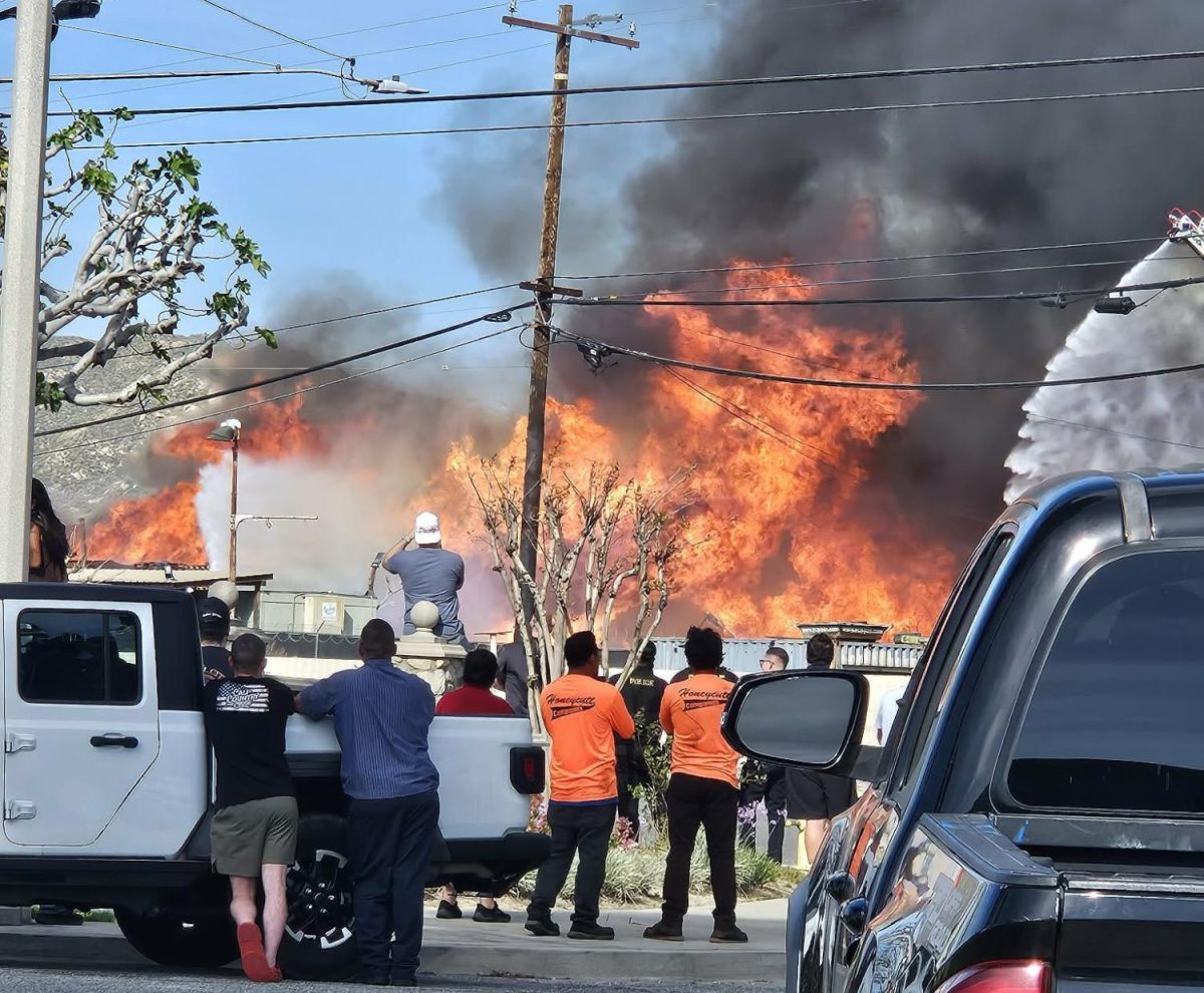 Evacuees stand just down the street watching as a wind-driven pallet fire consumes businesses on March 16 in Riverside.
