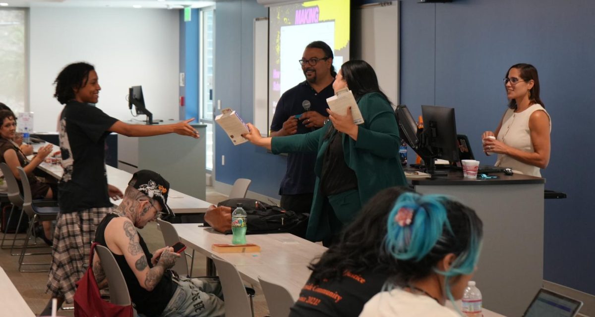 From left: Student receives a book from Raul Moreno, Citialli Anahuac and Parissa Clark at the "We Are Here Because You Were There" conference on May 7. 